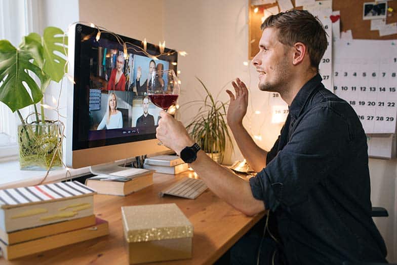 Guy enjoying virtual drinks with friends on video