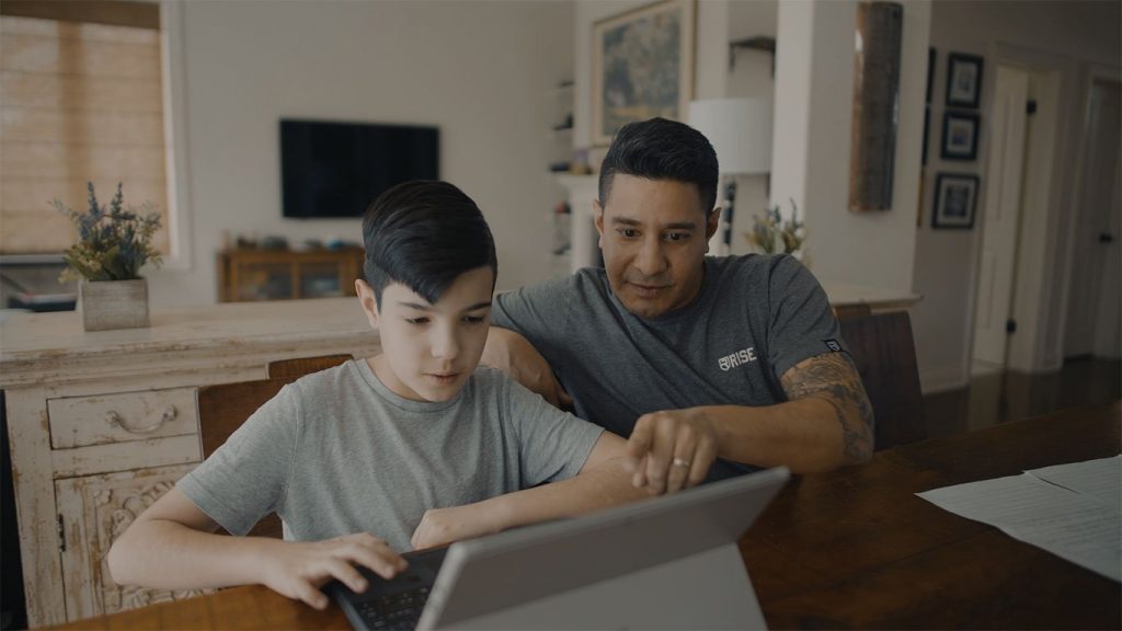 Dad teaching son to skateboard and be active outdoors