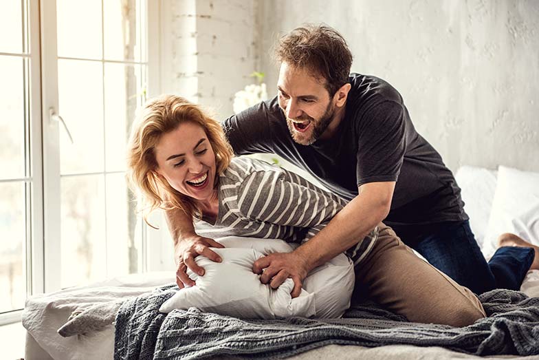 Couple horsin' around in bed
