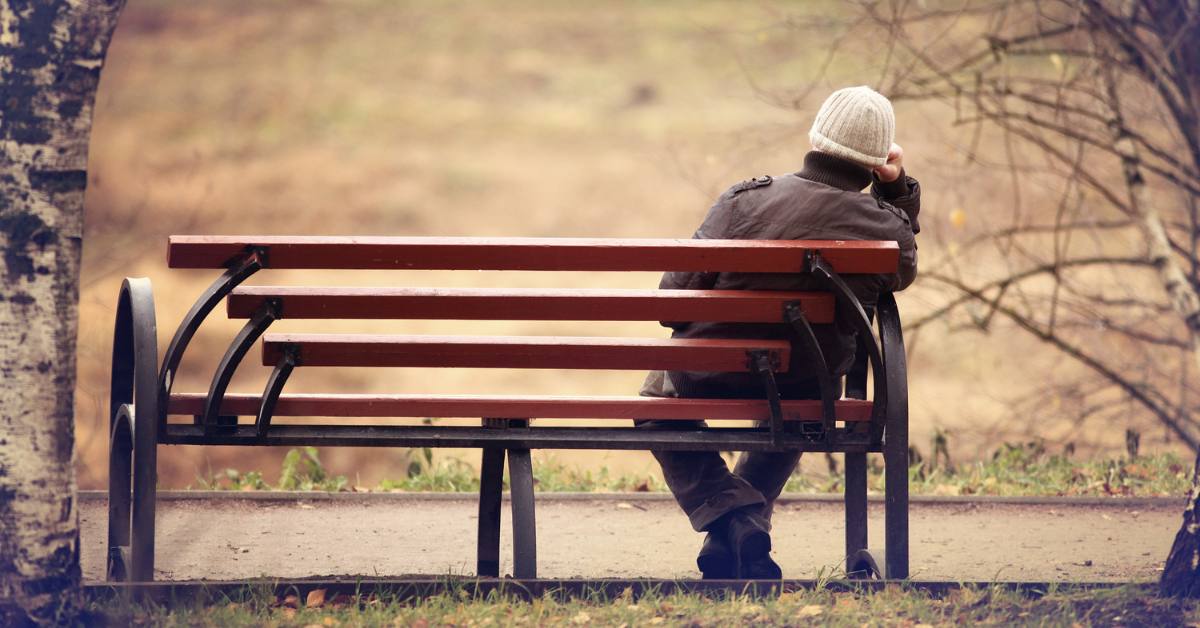 man sitting alone on bench in fall