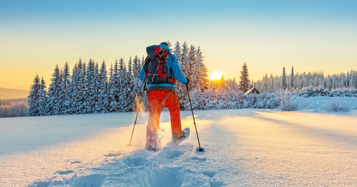 man snow shoeing at sunset