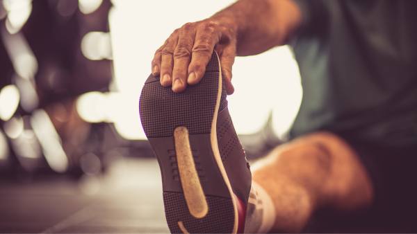 man stretching on floor close up of shoe and hand