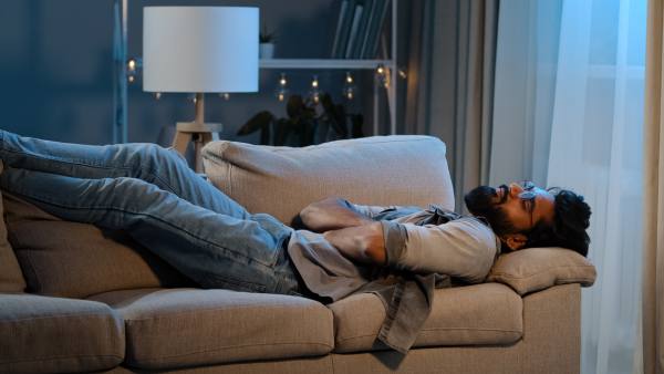 south asian man lying on cough in the dark