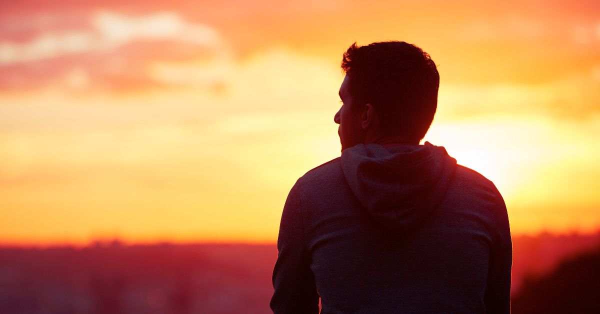 man sitting looking at sunset