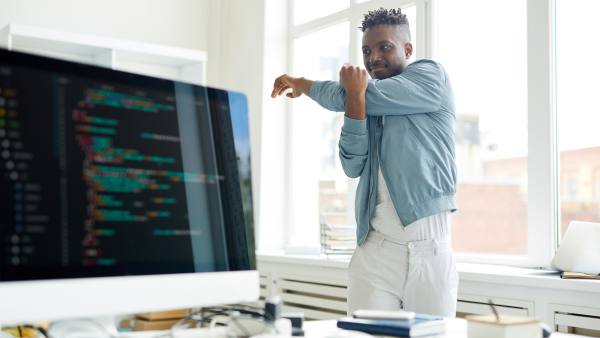man standing up at work desk to stretch
