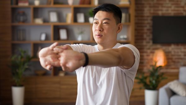 man stretching wrists with brick wall in background